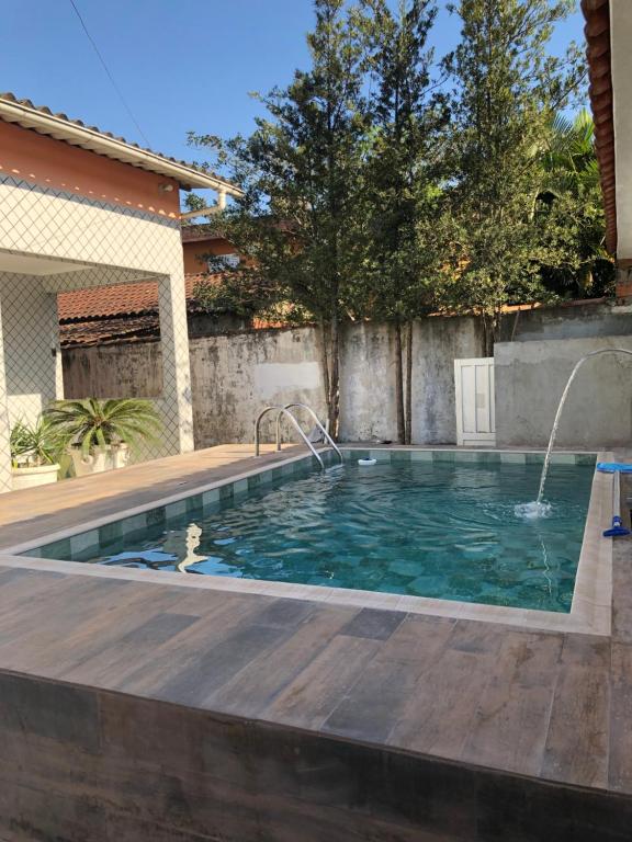 瓜鲁雅Casa espaçosa com Piscina e Churrasqueira 2 dorm的后院的游泳池,设有木甲板