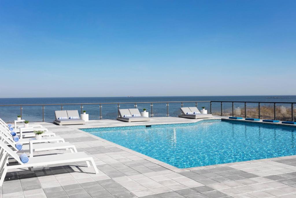 弗吉尼亚海滩Delta Hotels by Marriott Virginia Beach Waterfront的一个带躺椅的游泳池和海洋