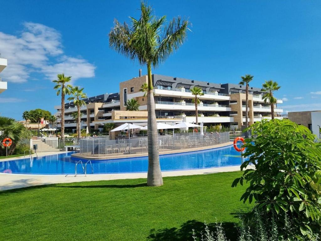 弗拉门卡海滩Flamenca Village Resort apt 172的一座建筑前的游泳池,里面种着棕榈树