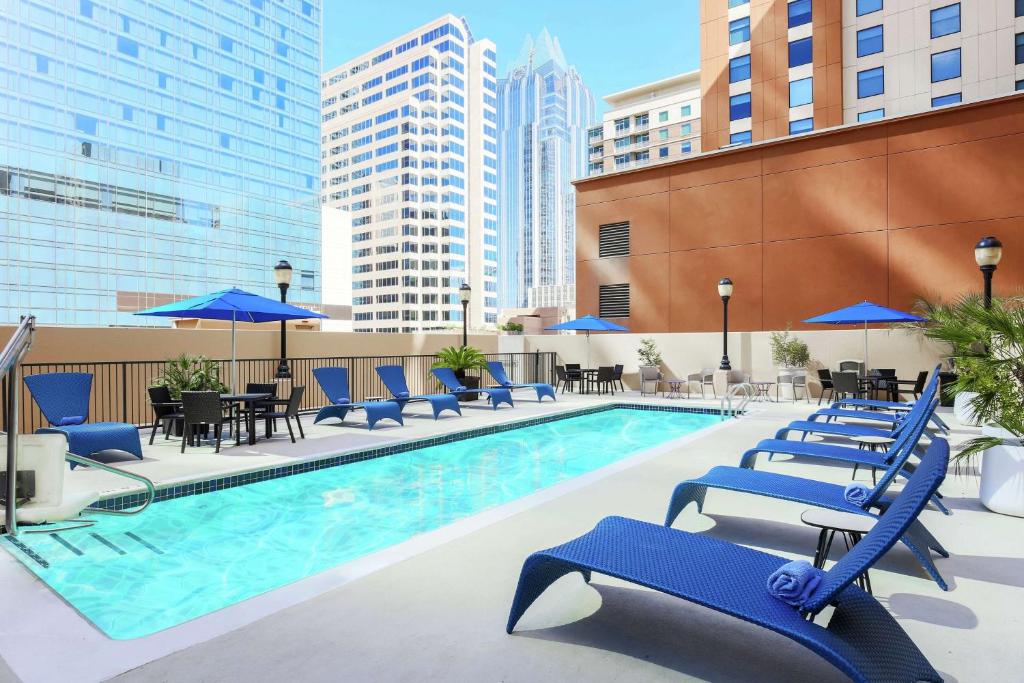 奥斯汀Hampton Inn & Suites Austin-Downtown/Convention Center的一个带蓝色桌椅和遮阳伞的游泳池