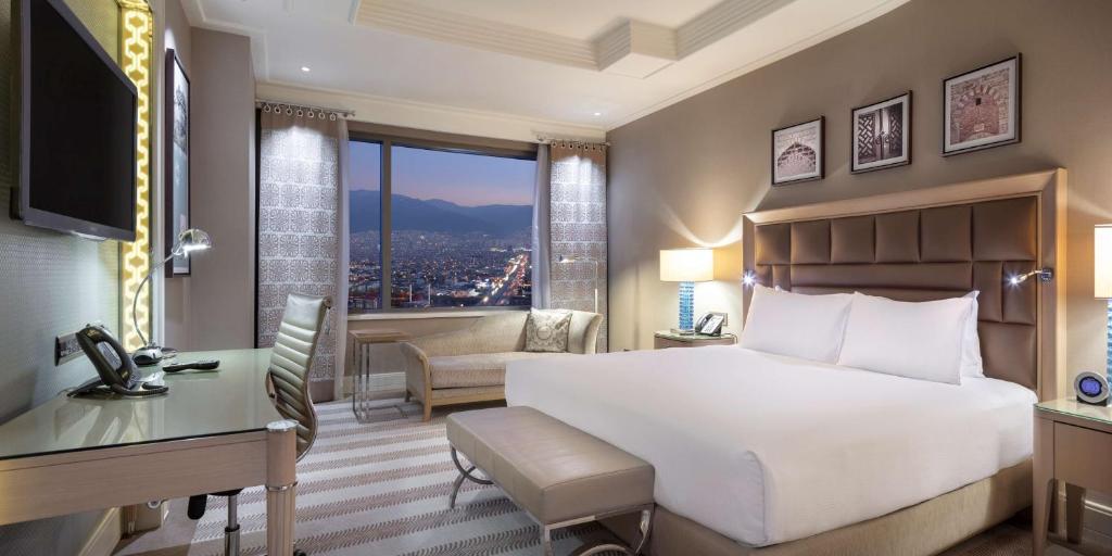 伯萨布尔萨希尔顿会议&Spa酒店的卧室配有一张白色大床、一张书桌和窗户。