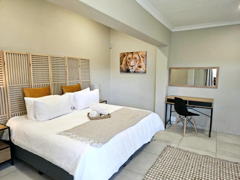 阿尔伯顿Bosveld In Die Stad Guesthouse的一间卧室配有一张大床和一张书桌