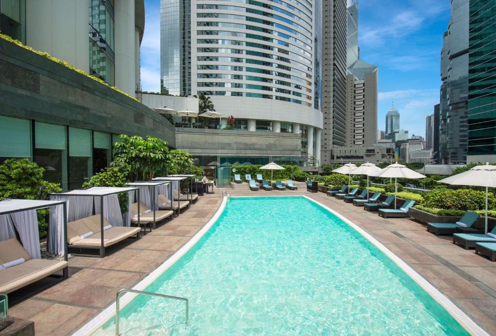 香港香港港丽酒店的城市里一个带椅子和遮阳伞的游泳池