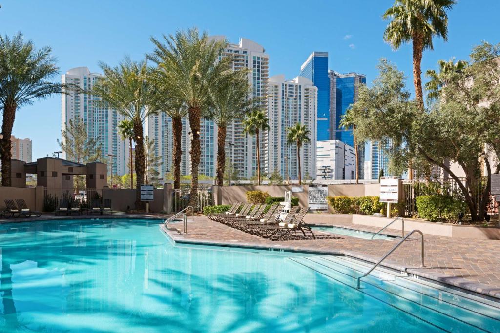拉斯维加斯Hilton Grand Vacations Club Paradise Las Vegas的一座棕榈树游泳池和城市天际线