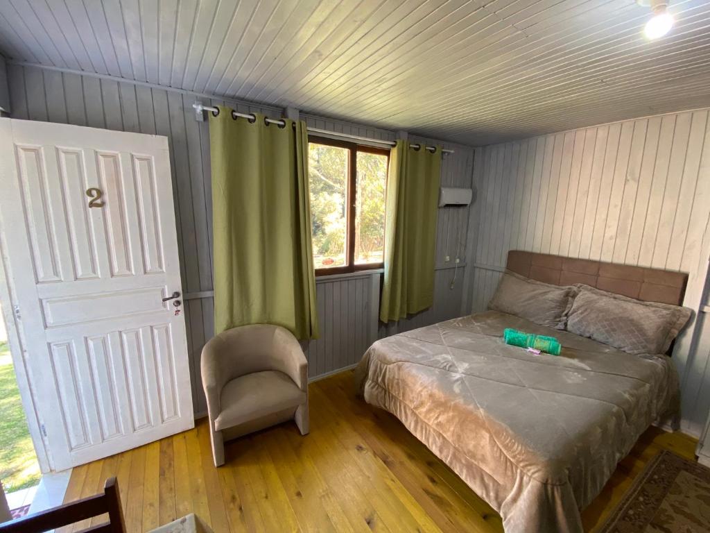乌鲁比西Cabana Pé Da Serra dos Bitus的卧室配有床、椅子和窗户。
