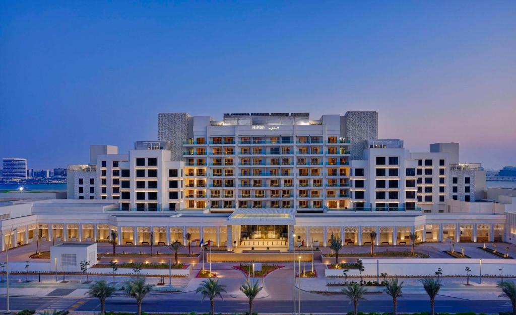 阿布扎比Hilton Abu Dhabi Yas Island的一座白色的大建筑,前面有棕榈树
