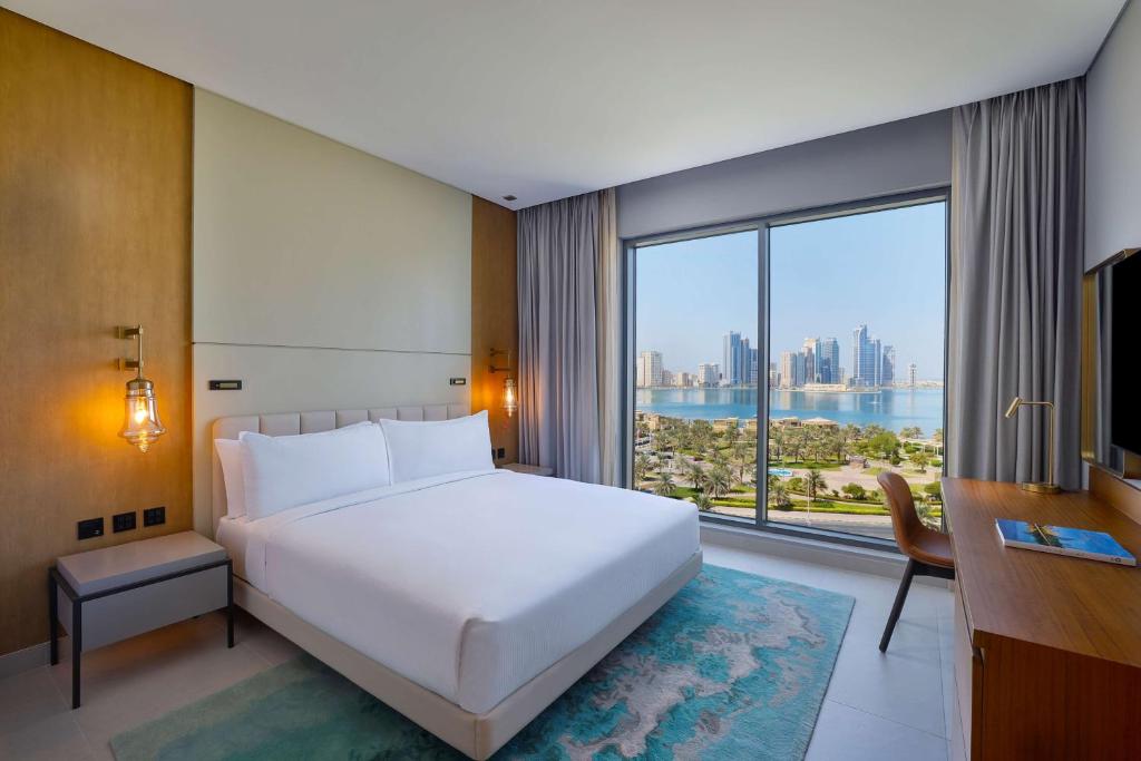 沙迦DoubleTree by Hilton Sharjah Waterfront Hotel And Residences的卧室设有一张白色大床和大窗户