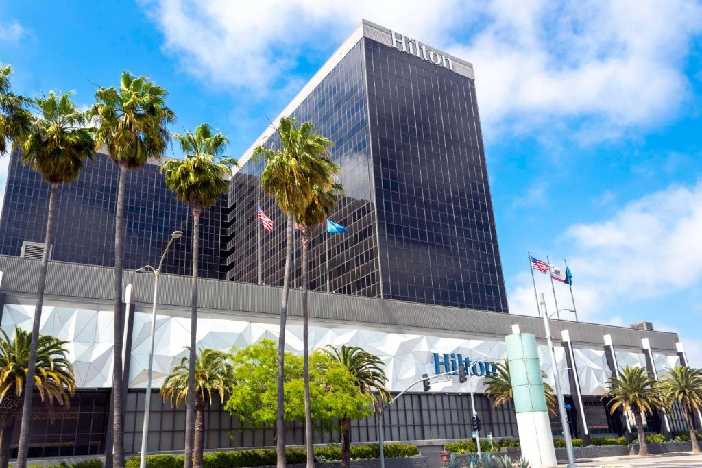 洛杉矶洛杉矶机场希尔顿酒店的一座高大的建筑,前面有棕榈树
