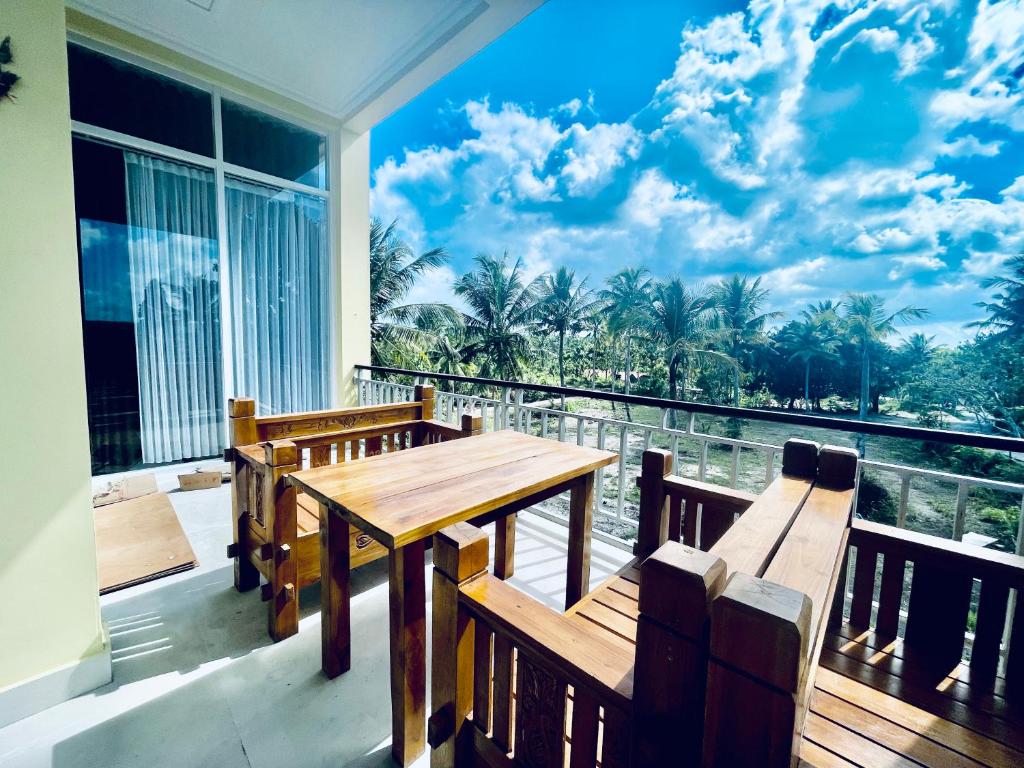 KlungkungKelingking Hostel的阳台配有木桌和2张长椅。