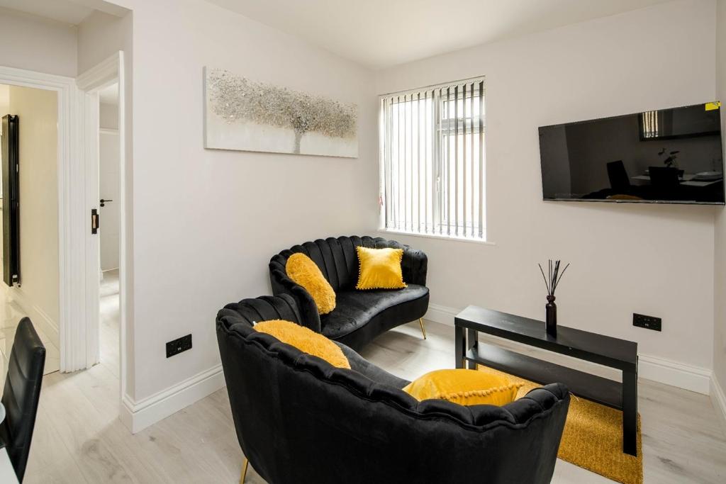 米查姆CommonSide Luxury的客厅配有黑色沙发和黄色枕头