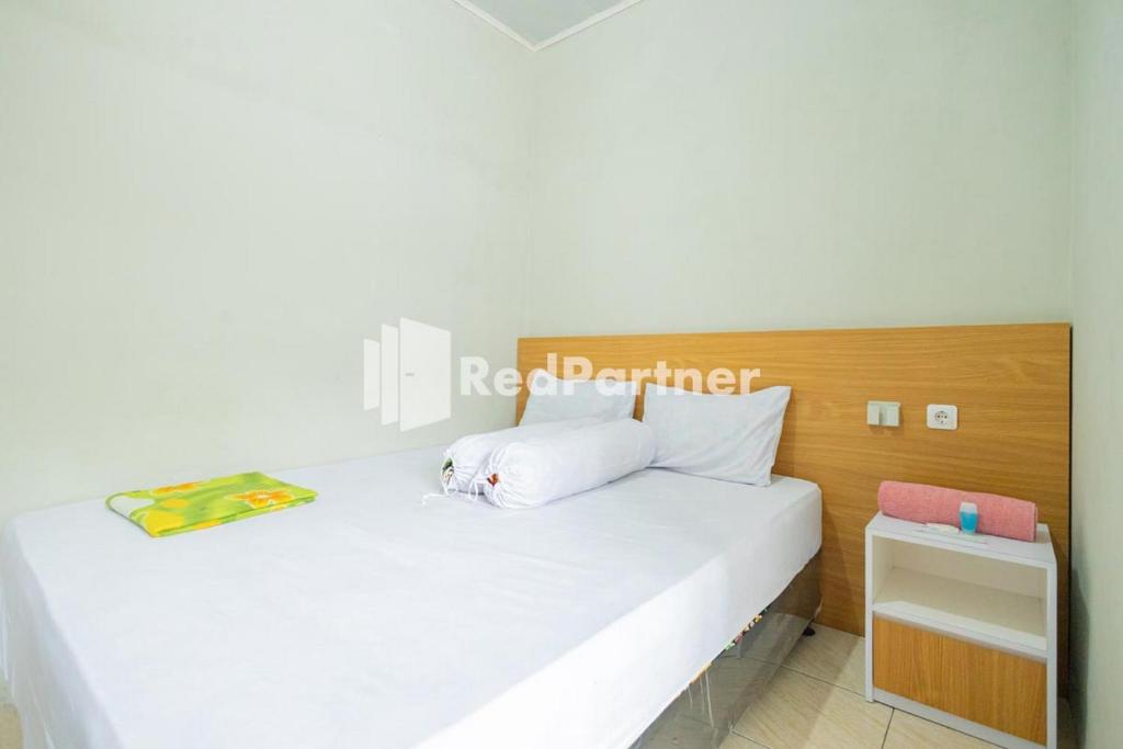 西冷Atiq Homestay Syariah Mitra RedDoorz的卧室配有白色的床和木制床头板