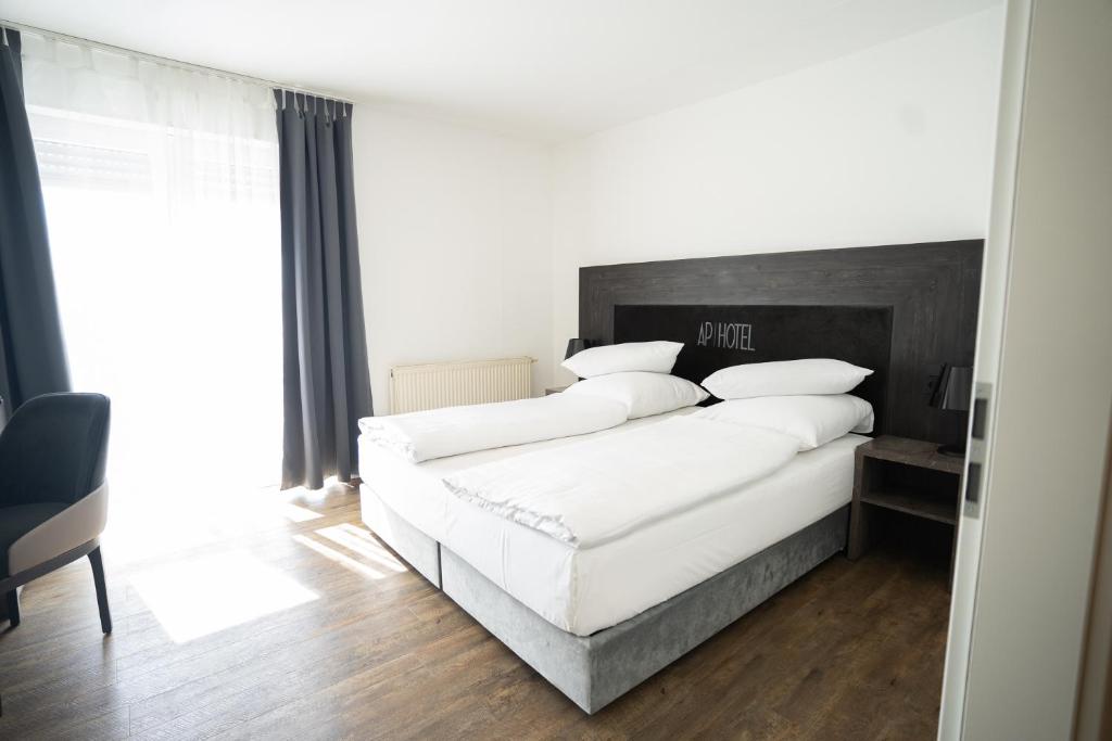 菲尔恩海姆AP Hotel Mannheim Viernheim的卧室配有白色大床和白色枕头