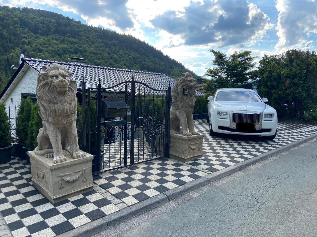 温特贝格VIP Haus Winterberg的狮子雕像旁边停泊的汽车