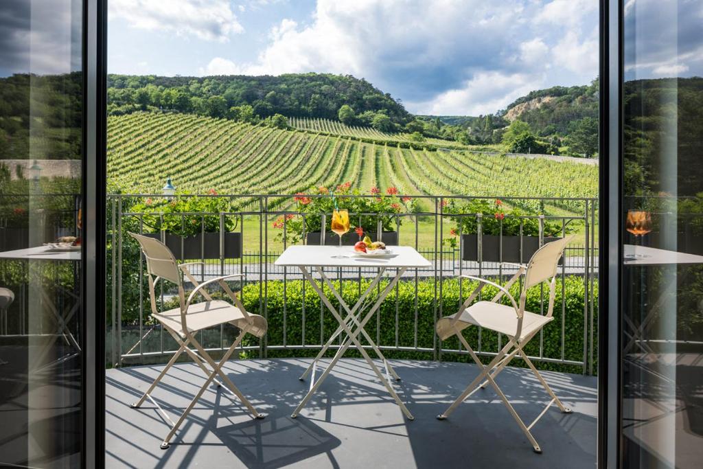 贡波尔德斯基兴登霍夫酒店的阳台配有桌椅,享有葡萄园的景致。