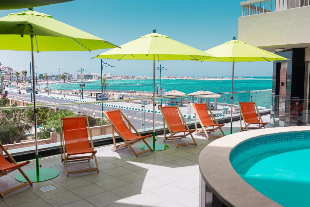 马特鲁港Delmar Hotel Matrouh的一组椅子和遮阳伞,位于游泳池旁