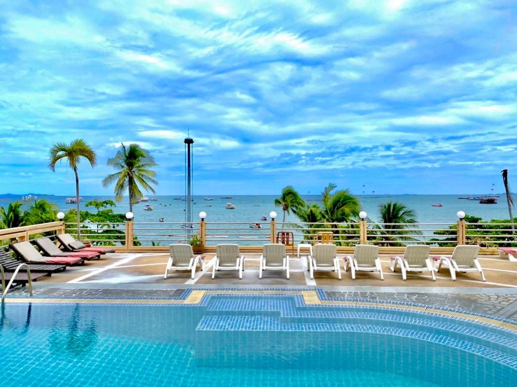芭堤雅市中心芭提雅AA酒店的一个带椅子的游泳池,背景是大海