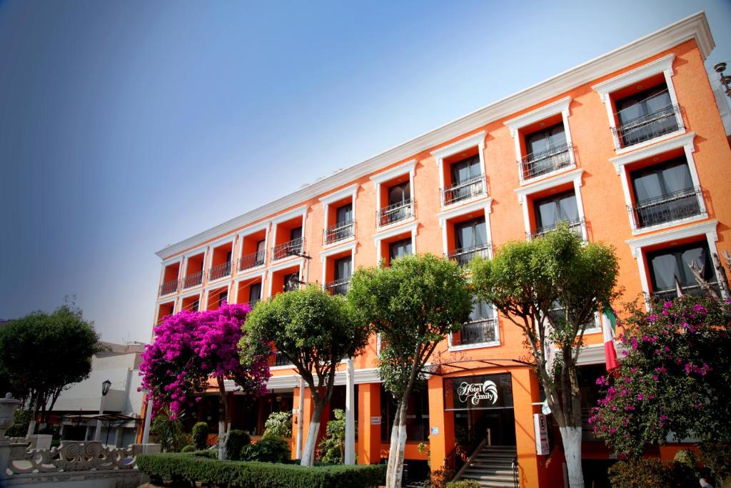 帕丘卡德索托艾米丽酒店的一座橘色的建筑,前面有树木