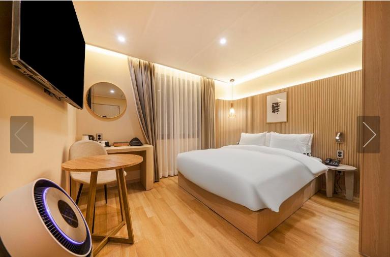 釜山Brown Dot Hotel Yeonsan的酒店客房设有一张大床和一张桌子。