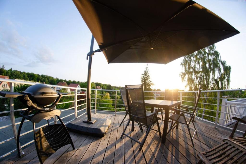 罗斯托克Weitblick-Loft mit Terrasse的庭院配有遮阳伞和桌椅。