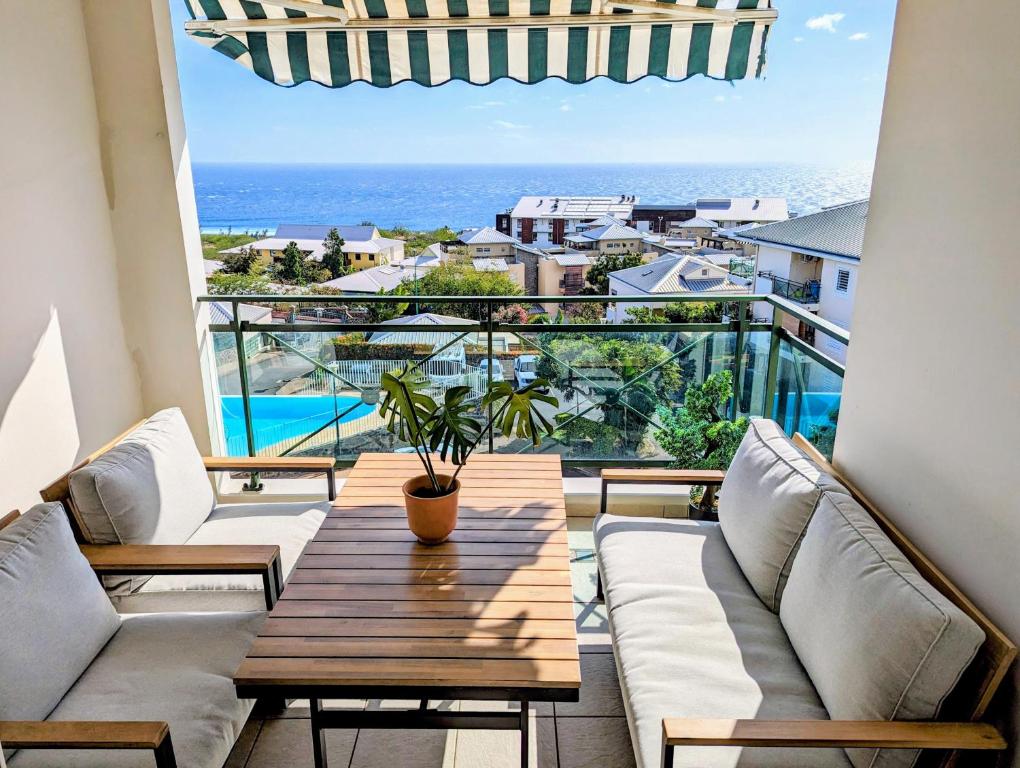 圣吉尔莱班Sunset Océan - appartement T2 avec vue imprenable sur l'océan et piscine的阳台配有桌子,享有海景。
