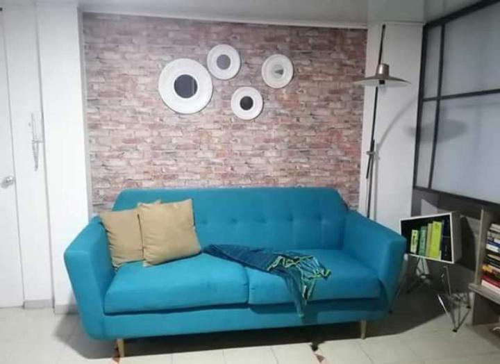 波哥大Cómoda y muy bien ubicada的客厅里设有蓝色的沙发,设有砖墙