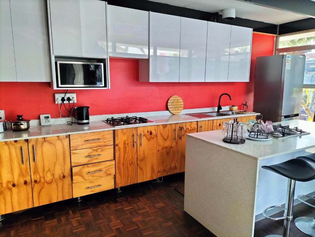 德班Inkanyezi guest house的厨房配有木制橱柜和红色的墙壁