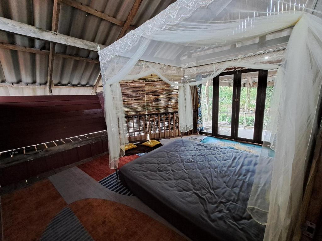 阁遥岛Big Hug Home-Nok kao house的一间带天蓬床的卧室,位于带窗户的房间内