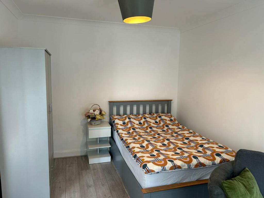 伦敦Room in Trumpington London的一间卧室配有一张床和一个带床罩的床头柜。