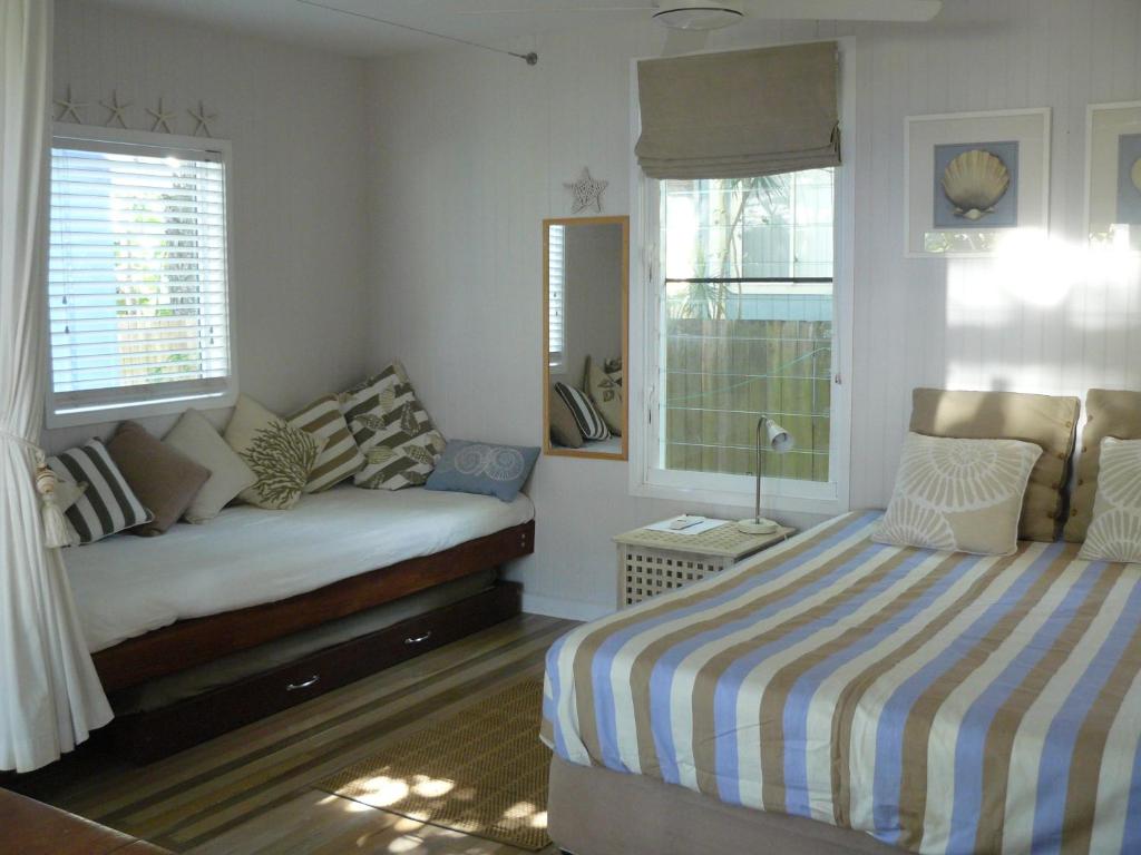Amity Point海窝棚旅馆的一间卧室设有一张床和两个窗户。