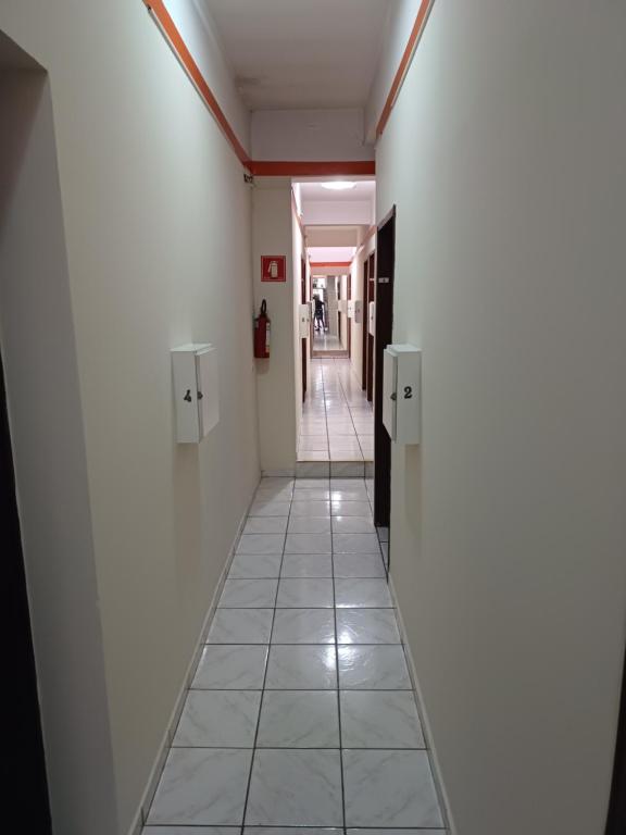 圣保罗Hotel coruja's的走廊设有白色墙壁和瓷砖地板