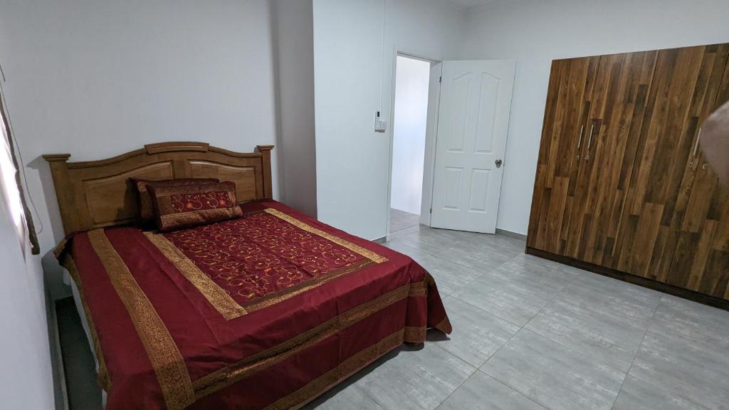 格兰高伯Haven Green Village的一间卧室配有一张带红色毯子和门的床