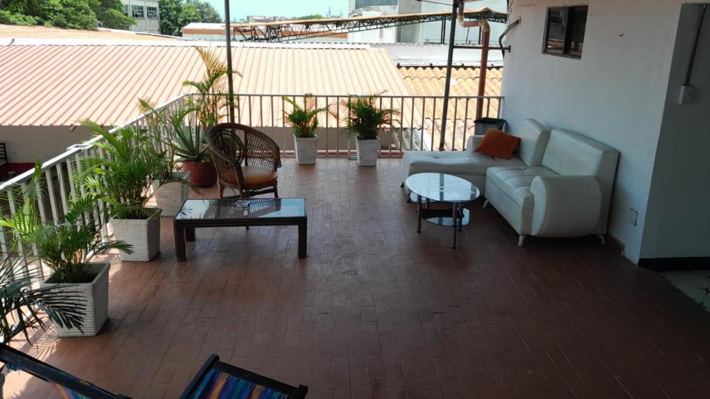 巴兰基亚HOTEL LA CORDIALIDAD的阳台配有沙发、桌子和盆栽植物