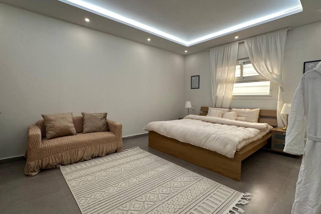 利雅德Modern cozy apartment的卧室配有床、椅子和窗户。