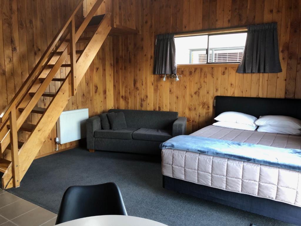 奥阿库尼高山汽车旅馆的一间卧室配有床、沙发和楼梯。