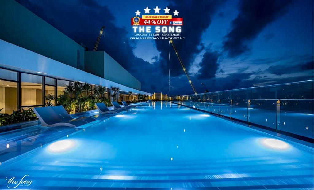头顿THE SONG VŨNG TÀU - Five-Star Luxury Apartment - Căn Hộ Du Lịch 5 Sao Cạnh Biển的夜间游泳池,带有读歌的标志