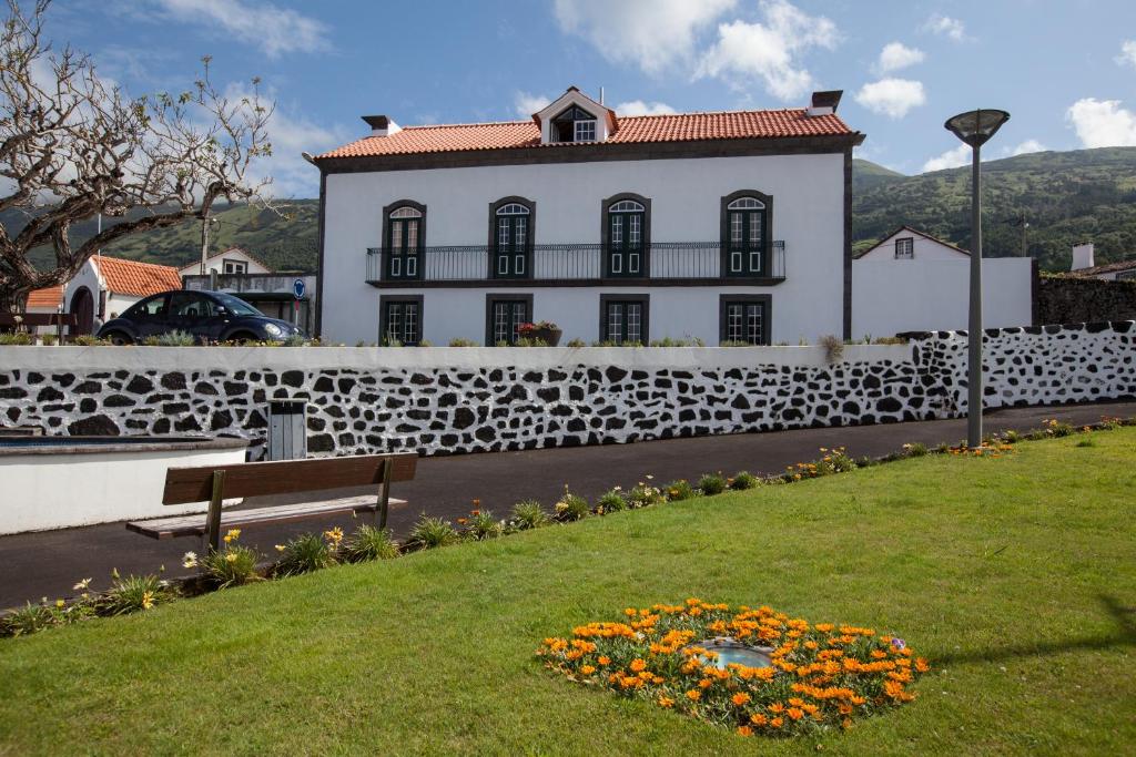 普赖尼亚德拜舒Pico da Saudade的白色的建筑,有栅栏、长凳和鲜花