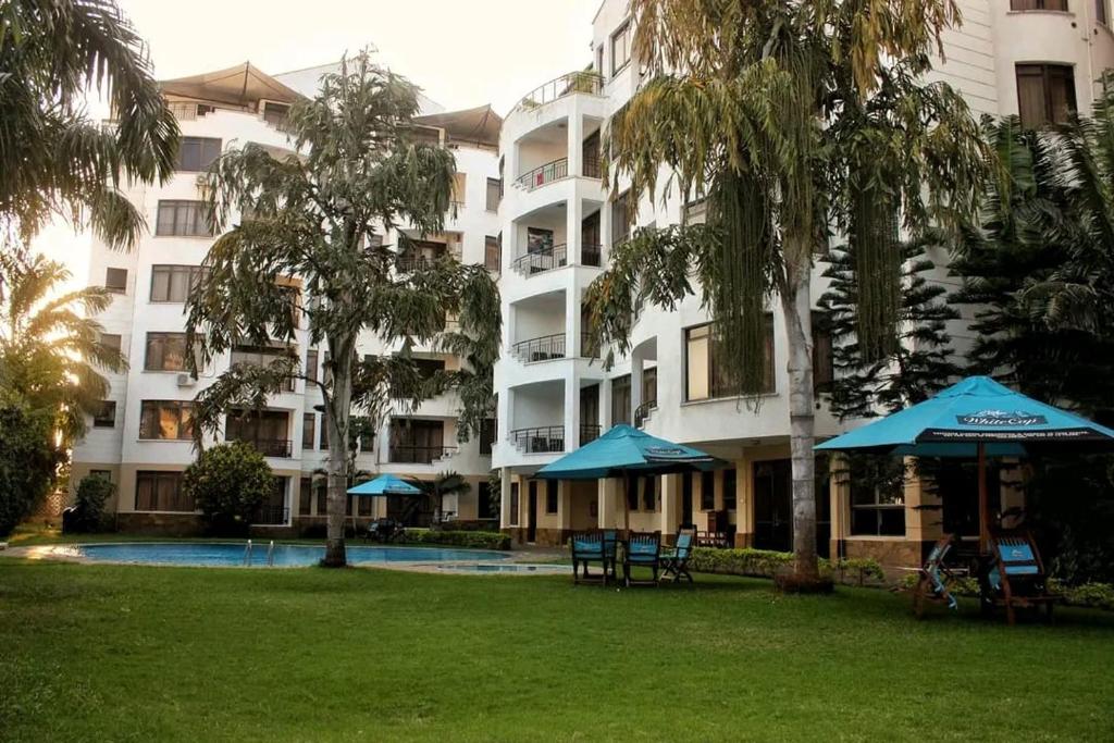 尼亚利Lux Suites Impala Apartments Nyali的公园里一座带遮阳伞的大型公寓楼