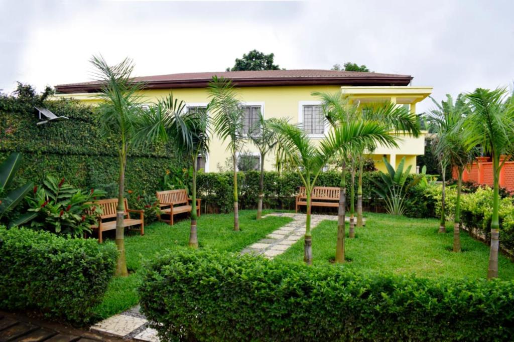 雅温得Riad Prince Louis的房屋前方的花园,种植了长椅和棕榈树