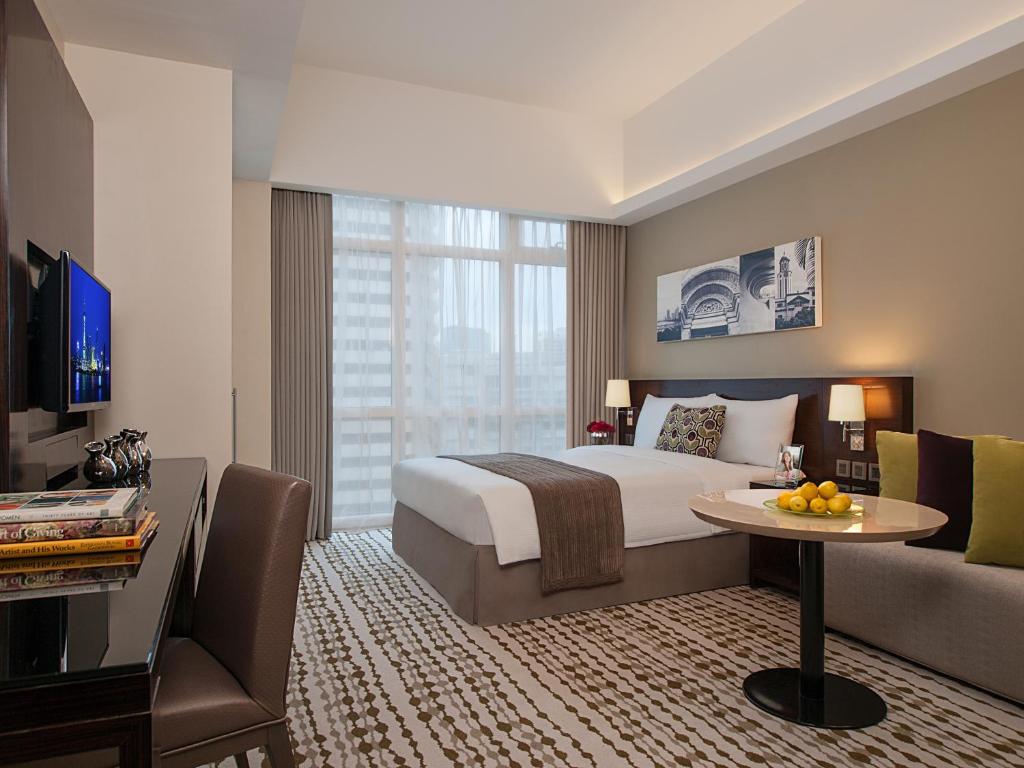 马尼拉Citadines Salcedo Makati的酒店客房配有床、桌子和沙发。