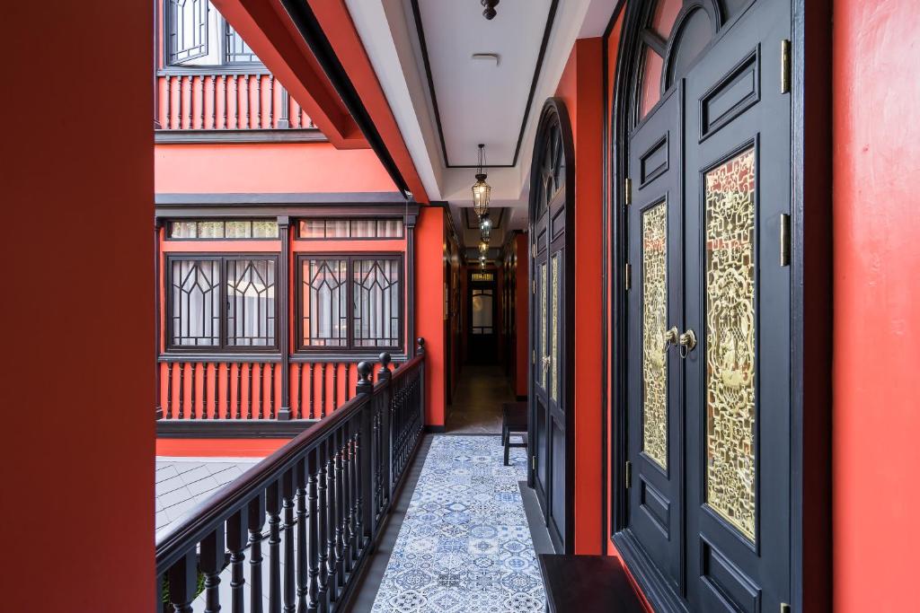曼谷DE Phanakron Boutique Hotel的走廊上设有红色和橙色的墙壁和门