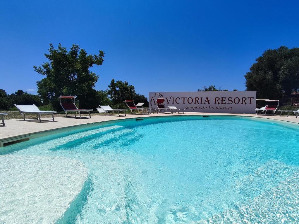 阿谢亚维多利亚度假酒店的绿化度假村标志前的大型游泳池