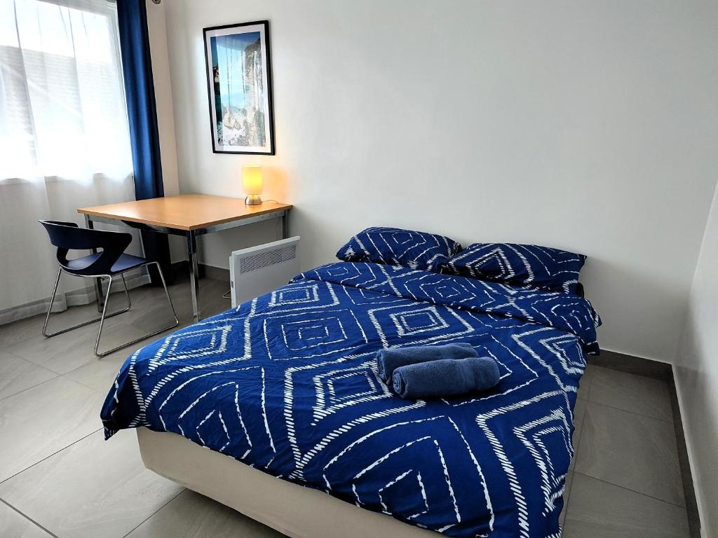 墨尔本PROMO!!! 2-Bedroom Home Near Airport, Train Station!的一间卧室配有一张带蓝色棉被的床和一张桌子