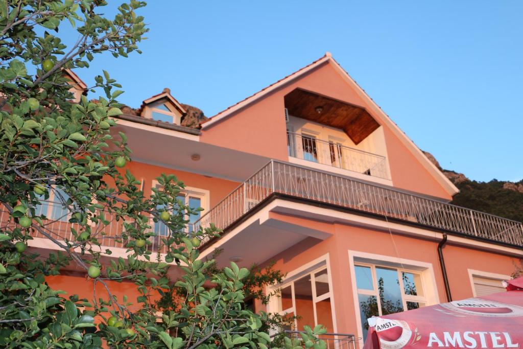 克鲁亚Villa Duka的带阳台和遮阳伞的橙色房子