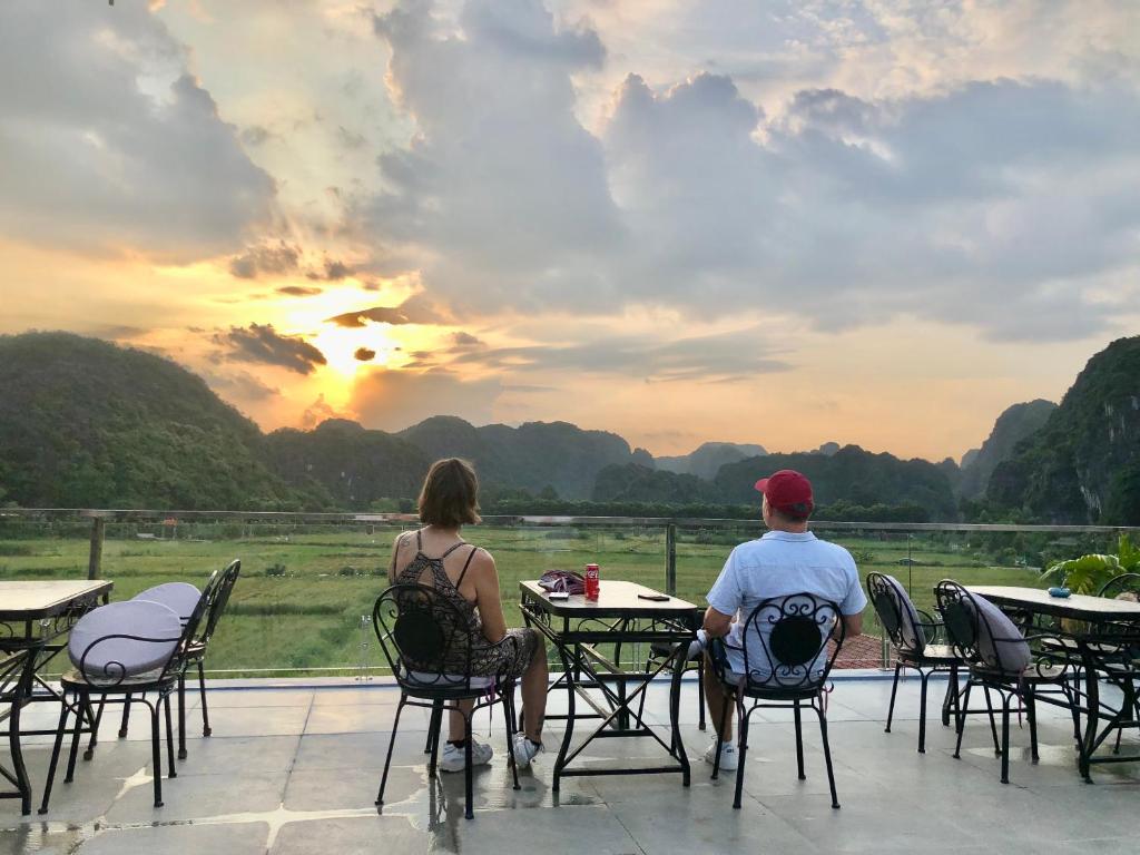 宁平Liberty Hall Tam Coc Hotel & Villa的坐在桌子旁观看日落的男人和女人