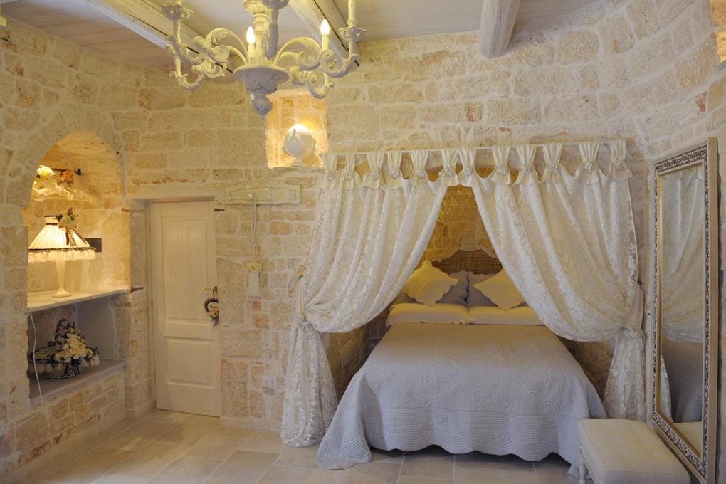 阿尔贝罗贝洛浪漫特鲁利酒店的一间卧室配有一张白色天蓬床