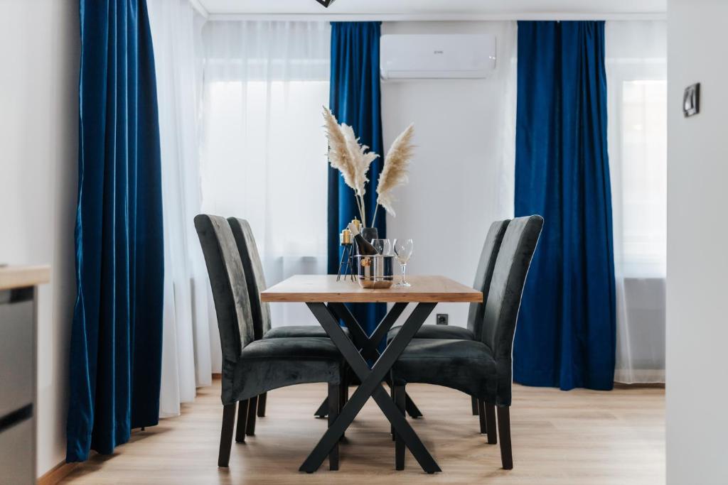 布尔奇科Modern Lux Apartment 2的一张带黑色椅子和蓝色窗帘的餐桌