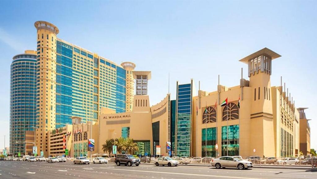 阿布扎比International Abu Dhabi Hostel的一座大型建筑,前面有汽车停放
