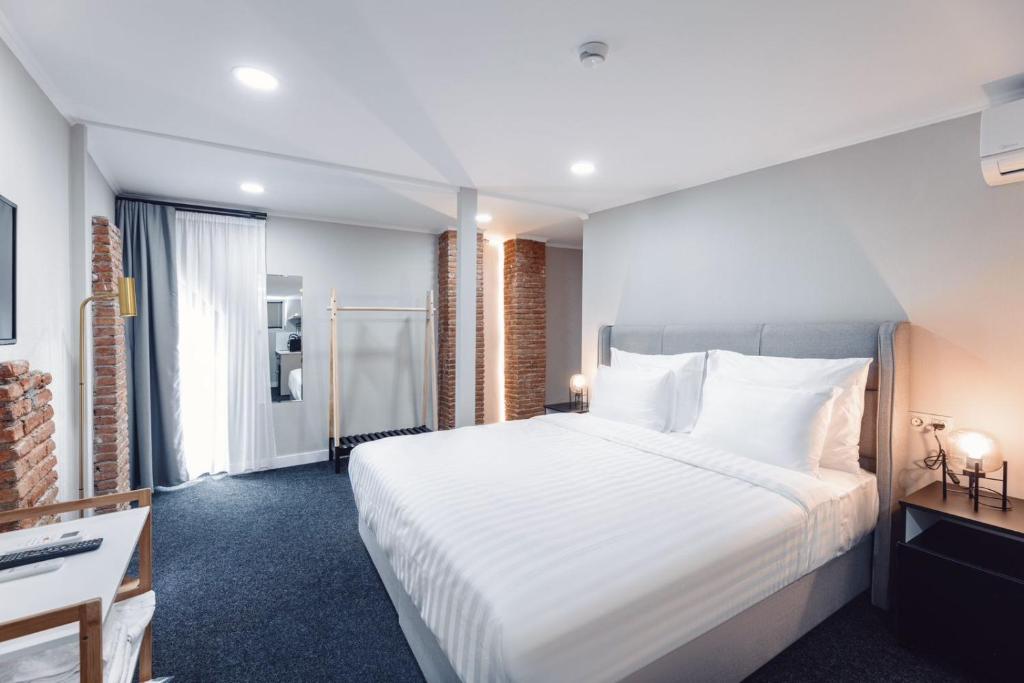 第比利斯Salve的酒店客房设有一张白色大床和一张书桌