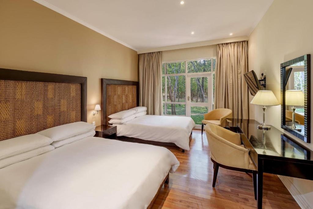 Chisamba普罗蒂亚野生酒店的酒店客房设有两张床、一张桌子和一台电视。