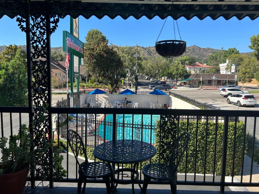 洛杉矶迎宾住宿加早餐旅馆的阳台配有桌椅,享有泳池美景